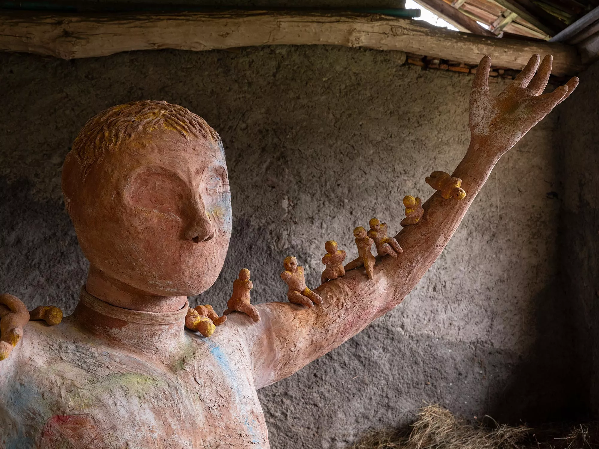 Gaia Fugazza - Gaia Fugazza, Mother of Millions, 2025, detail of small human figures arranged along the arm of an Impruneta clay sculpture, with engravings on the head and chest.