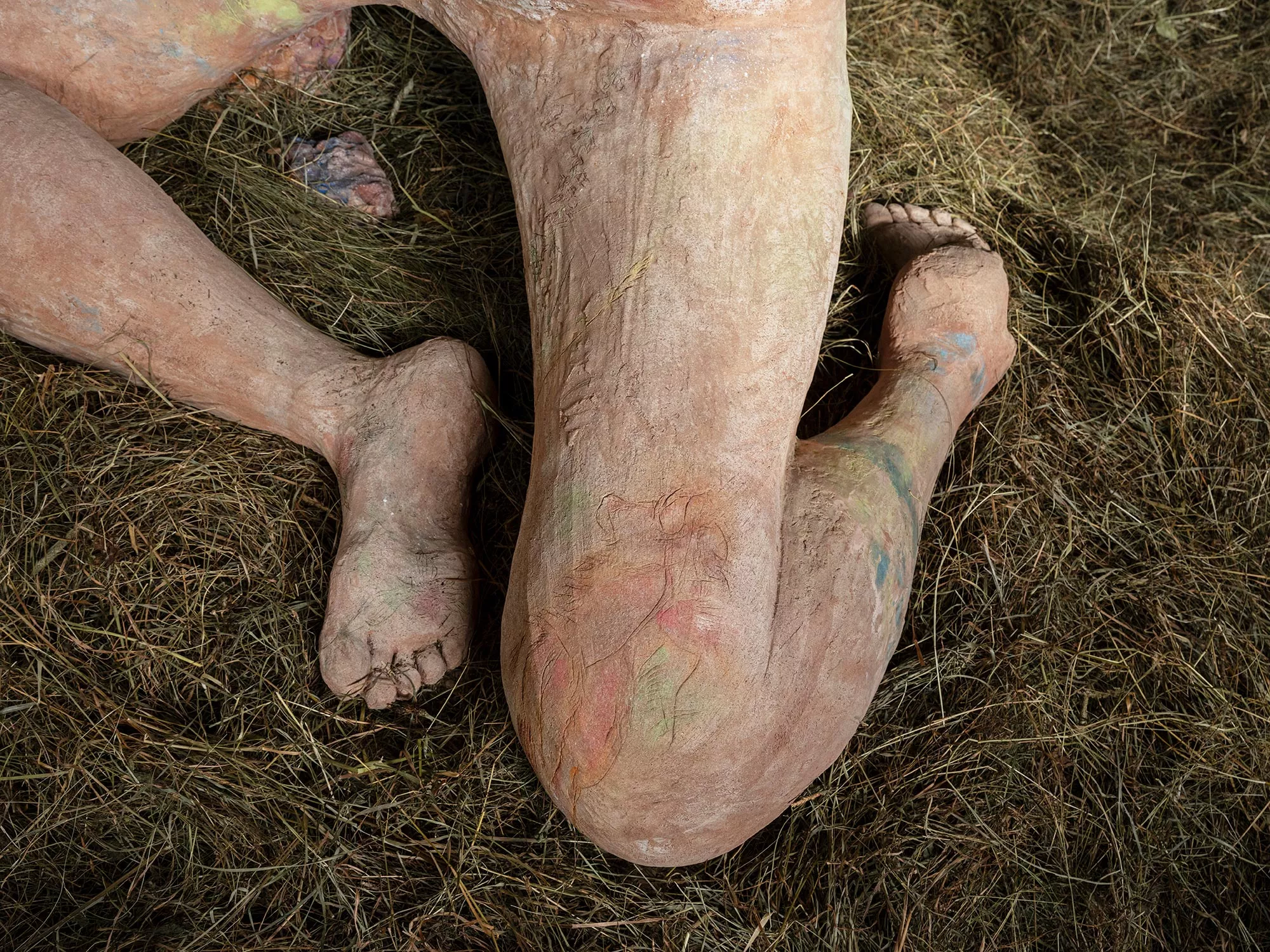 Gaia Fugazza - Gaia Fugazza, Mother of Millions, 2025, detail of the large sculpture’s folded legs and feet resting on hay.