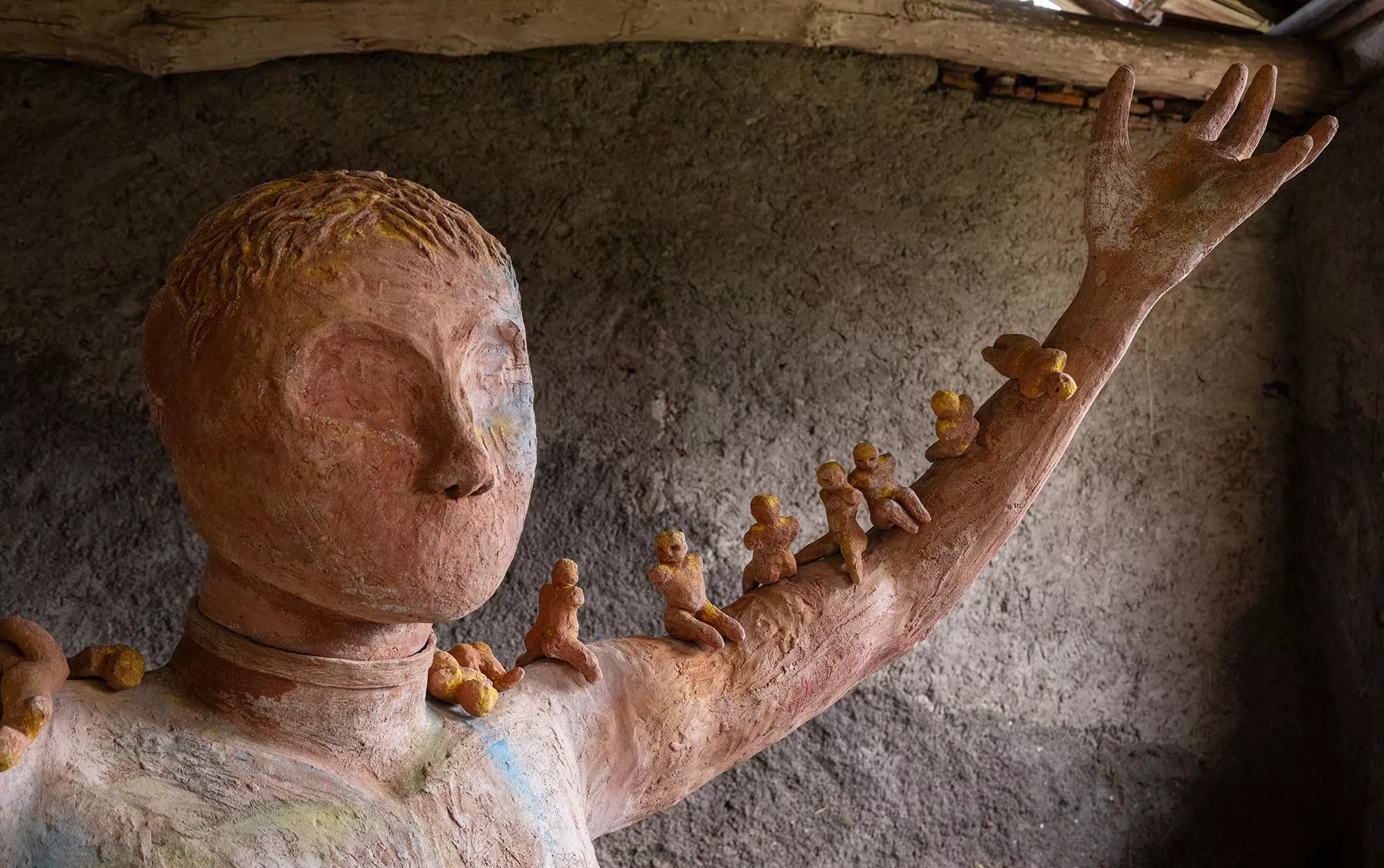 Gaia Fugazza - Gaia Fugazza, Mother of Millions, 2025, detail of small human figures arranged along the arm of an Impruneta clay sculpture, with engravings on the head and chest.