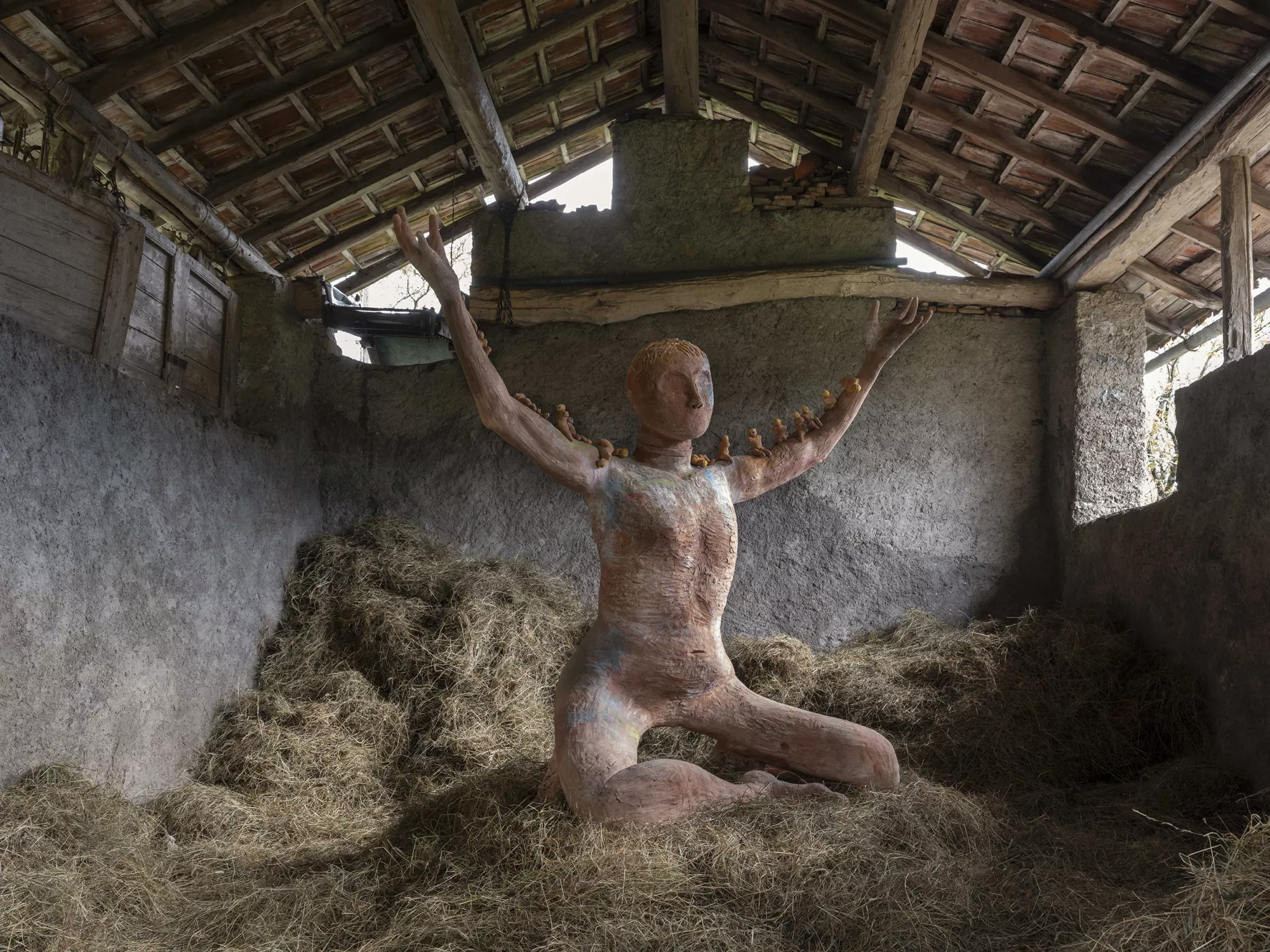 Gaia Fugazza - Gaia Fugazza, Mother of Millions, 2025, Impruneta clay sculpture, a monumental human form inspired by the Mother of Millions plant, with small figures along its arms and engravings depicting transhumance and the alpine environment.